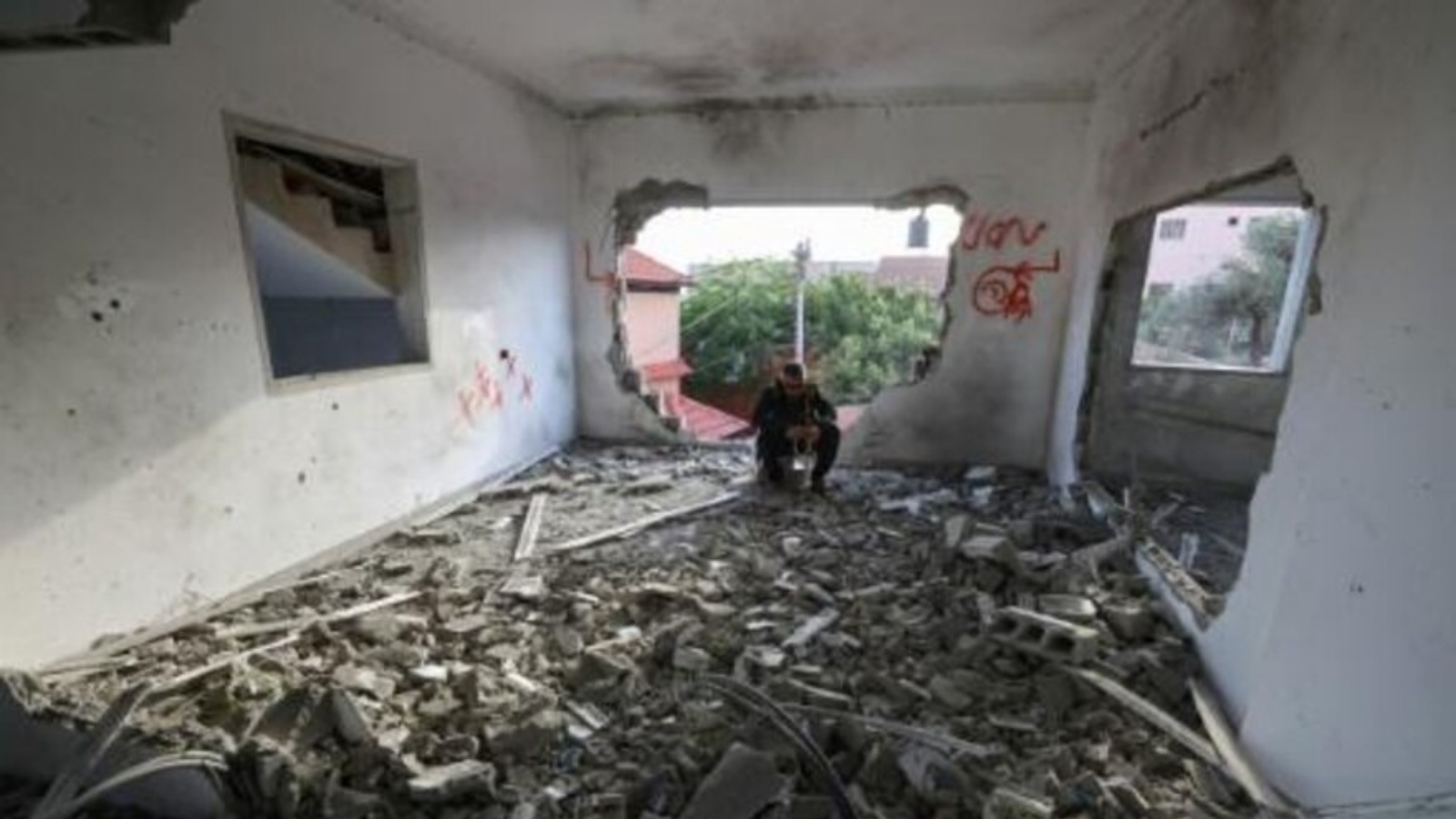  فلسطيني جالس في منزل عمر جرادات بعدما دمرته القوات الإسرائيلية في بلدة السيلة الحارثية قرب جنين في الضفة الغربية المحتلة في 7 مايو 2022