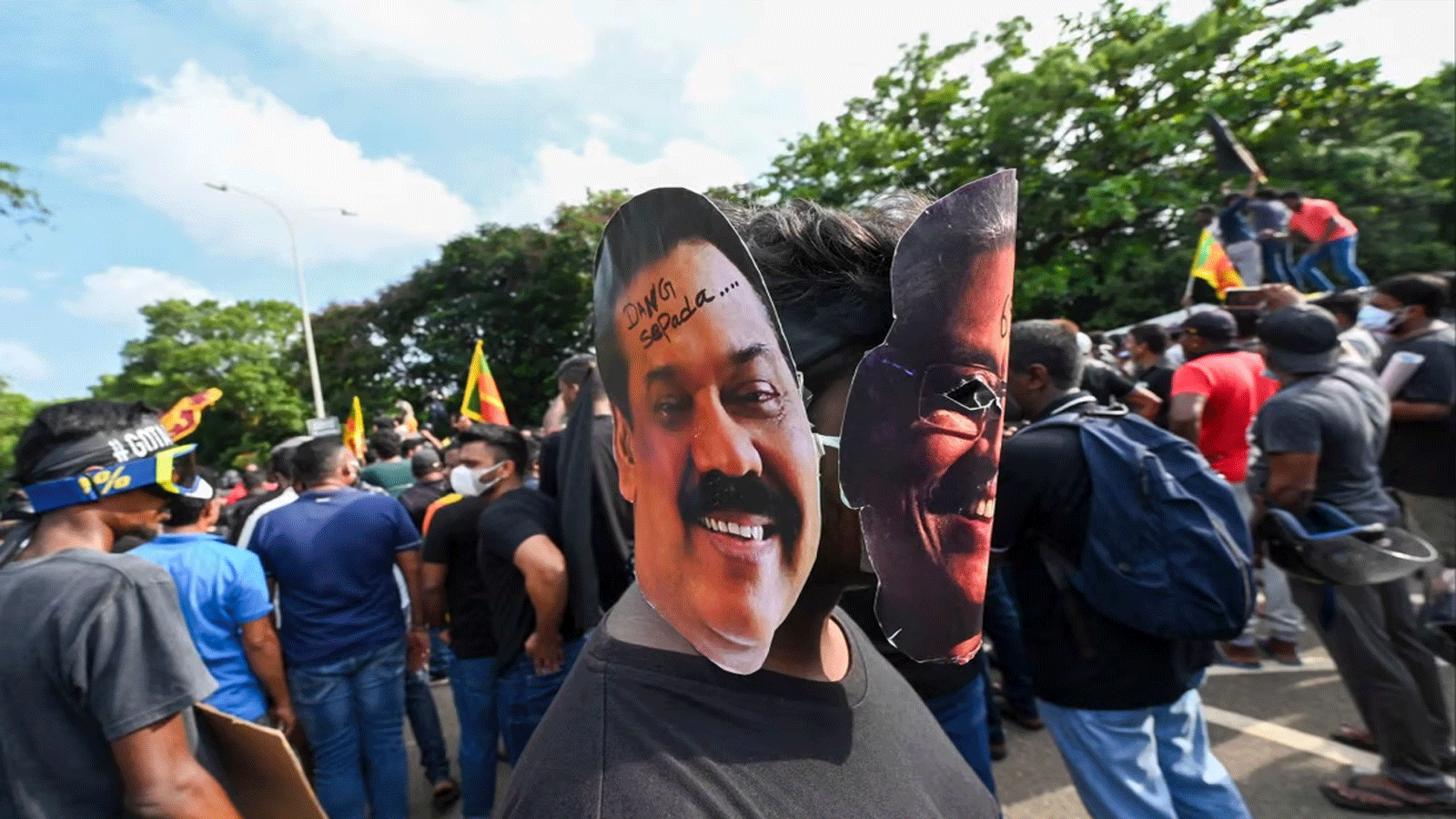 متظاهر يرتدي أقنعة رئيس سريلانكا جوتابايا راجاباكسا (يمين) ورئيس الوزراء ماهيندا راجاباكسا