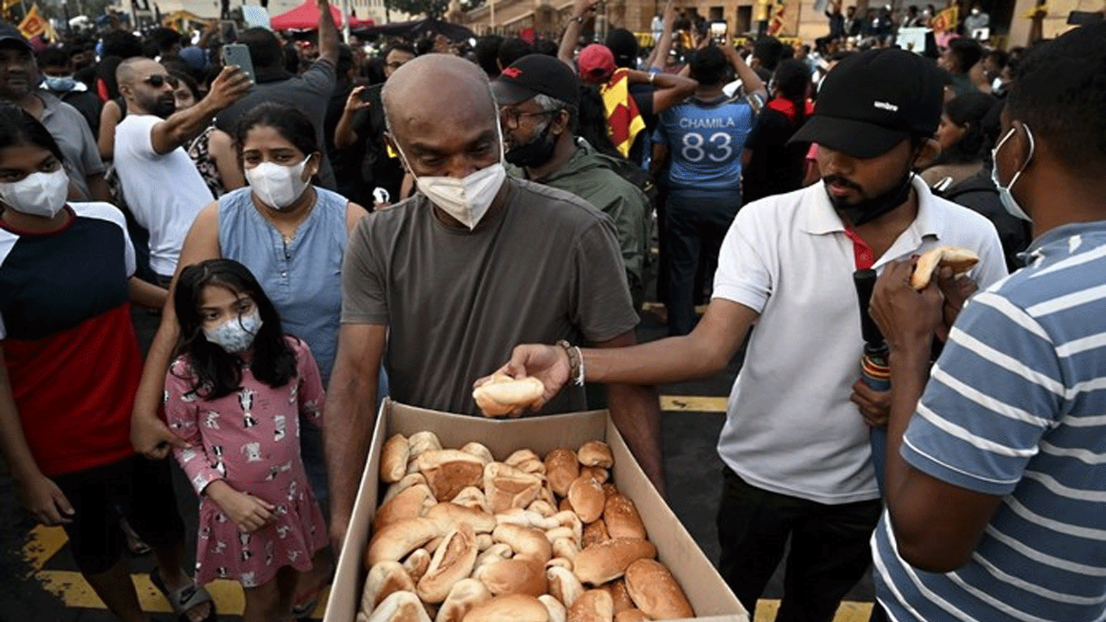 رجلُ يقدم طعامًا مجانيًا للمتظاهرين أثناء مشاركتهم في احتجاج على الأزمة الاقتصادية عند مدخل مكتب الرئيس في كولومبو.