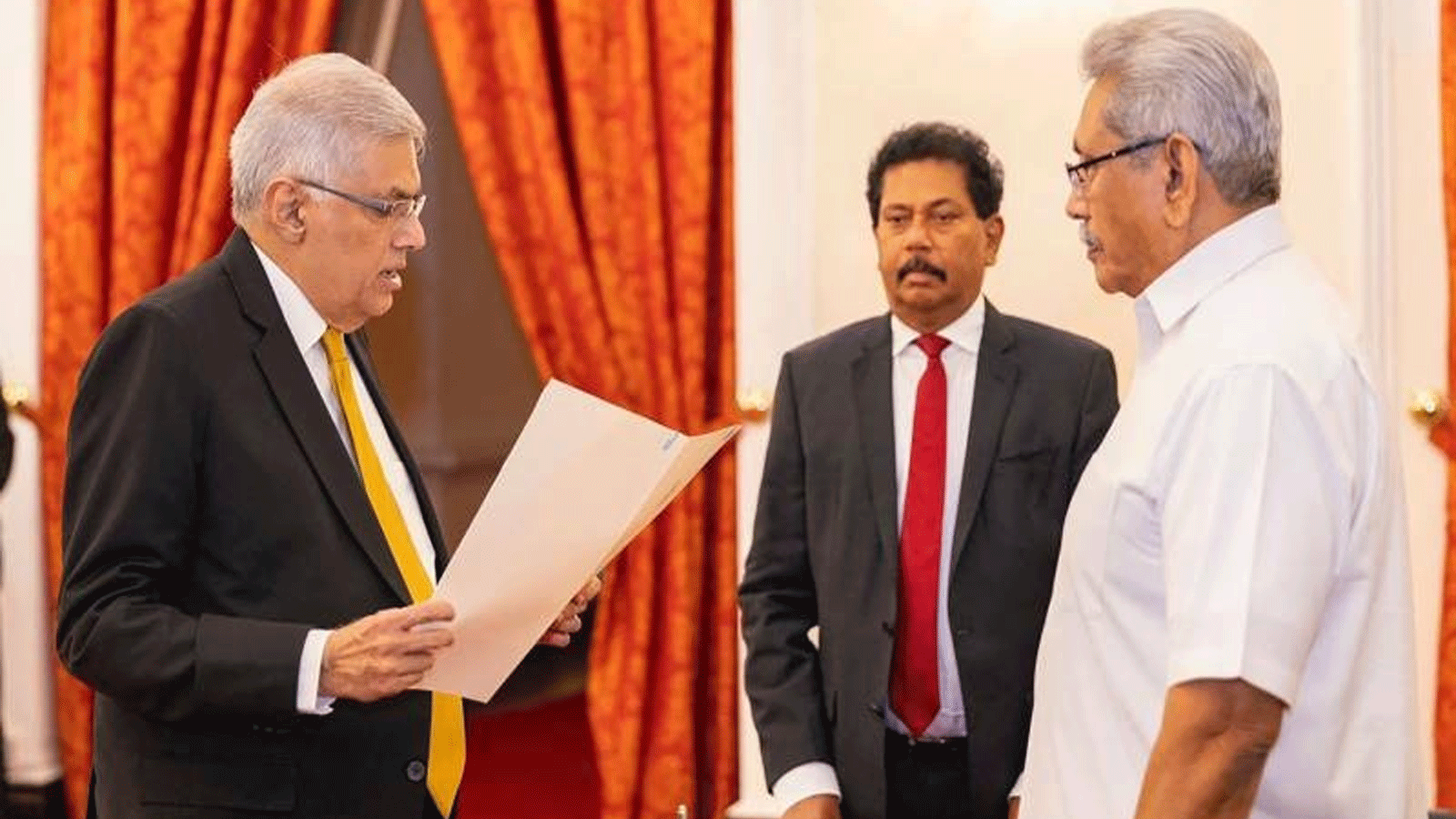 يُظهر مكتب رئيس سريلانكا رئيس الوزراء الجديد رانيل ويكرمسينغ (إلى اليسار) يحضر أداء اليمين أمام الرئيس جوتابايا راجاباكسا (إلى اليمين) في قصر الرئيس في كولومبو