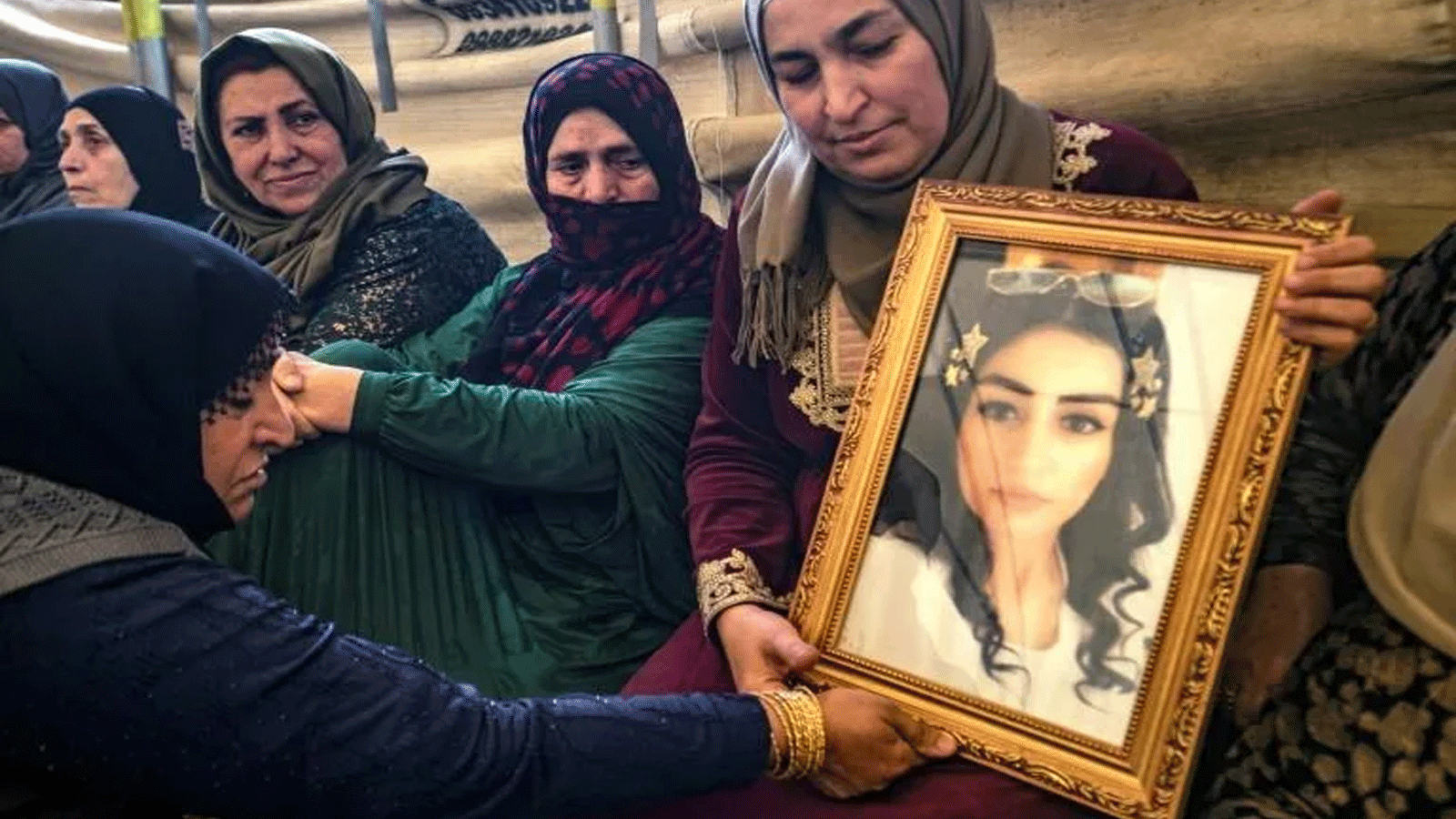  هيام سعدون تحمل صورة ابنتها إيناس عبد السلام البالغة من العمر 23 عامًا والمذكورة في عداد المفقودين مع صديقتها جيندة سعيد، 27 عامًا، بعد محاولتهما الوصول إلى أوروبا.