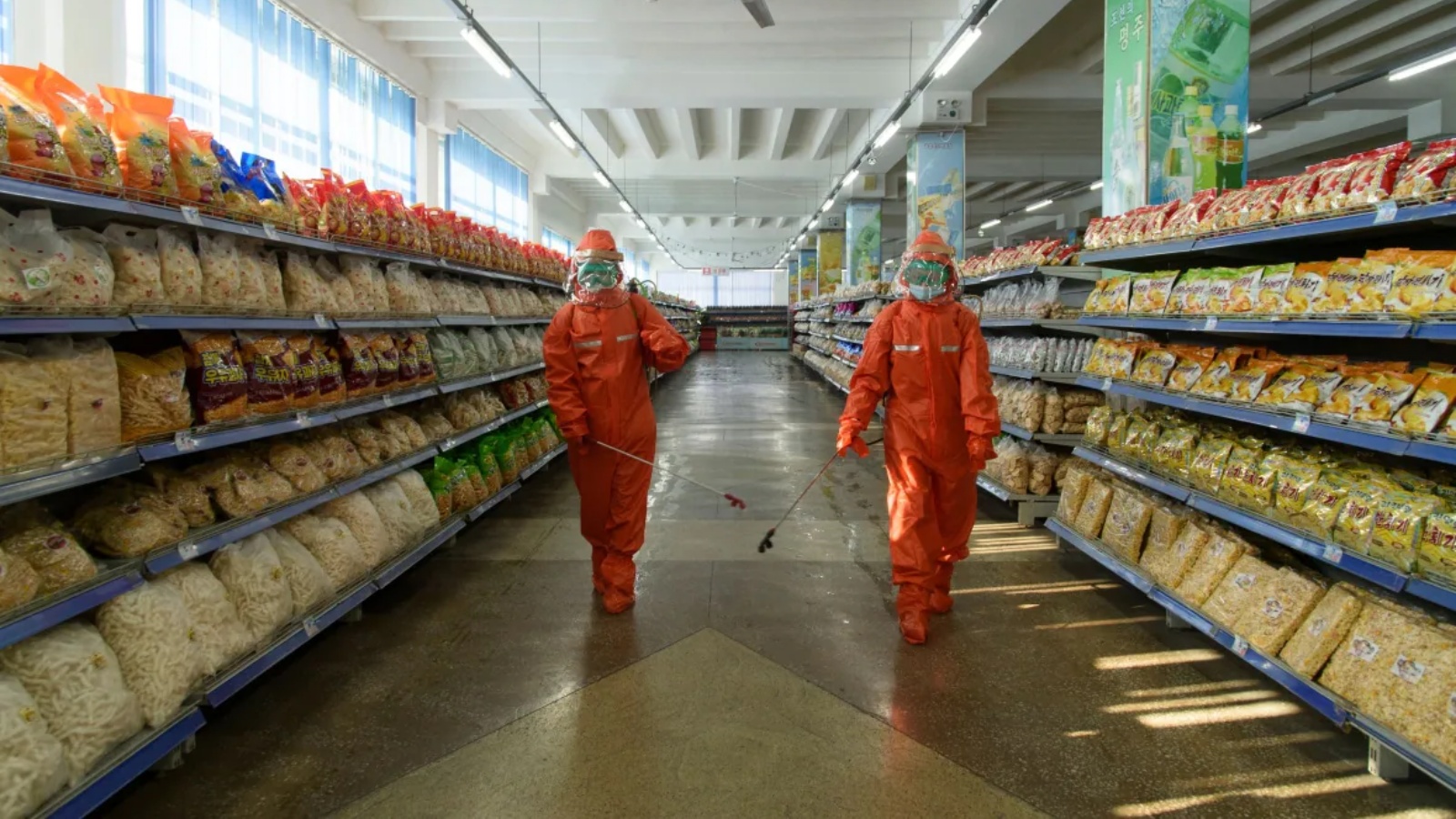 عاملا صحة يقومان بتعقيم الرفوف والأرضيات في متجر لبيع المواد الغذائية في بيونغ يانغ