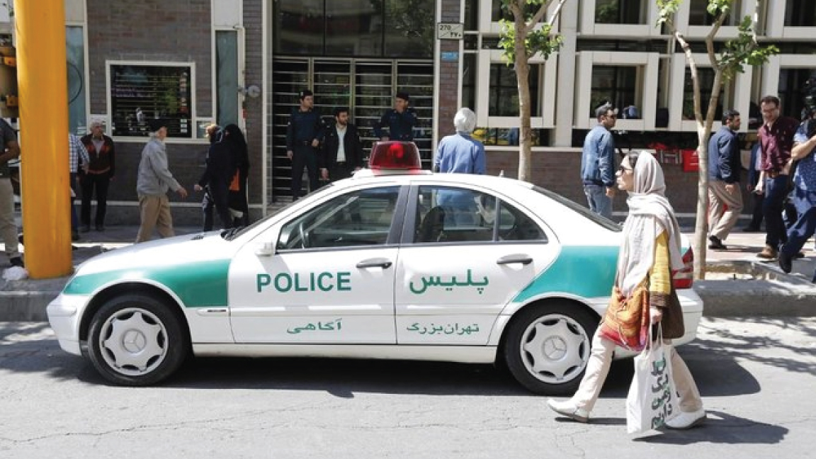 صورة من الأرشيف لامرأة إيرانية تمر بسيارة للشرطة في أحد شوارع طهران