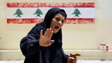 ناخبة تظهر إبهامها الملطخ بالحبر بعد الإدلاء بصوتها في الانتخابات النيابية في مركز اقتراع في مدينة طرابلس شمال لبنان، في 15 مايو 2022