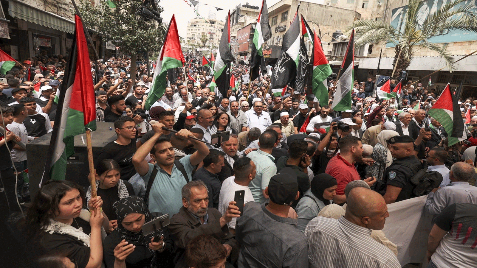  فلسطينيون يلوحون بالأعلام الوطنية وهم يسيرون في مسيرة لإحياء الذكرى 74 للنكبة في بلدة رام الله المحتلة بالضفة الغربية