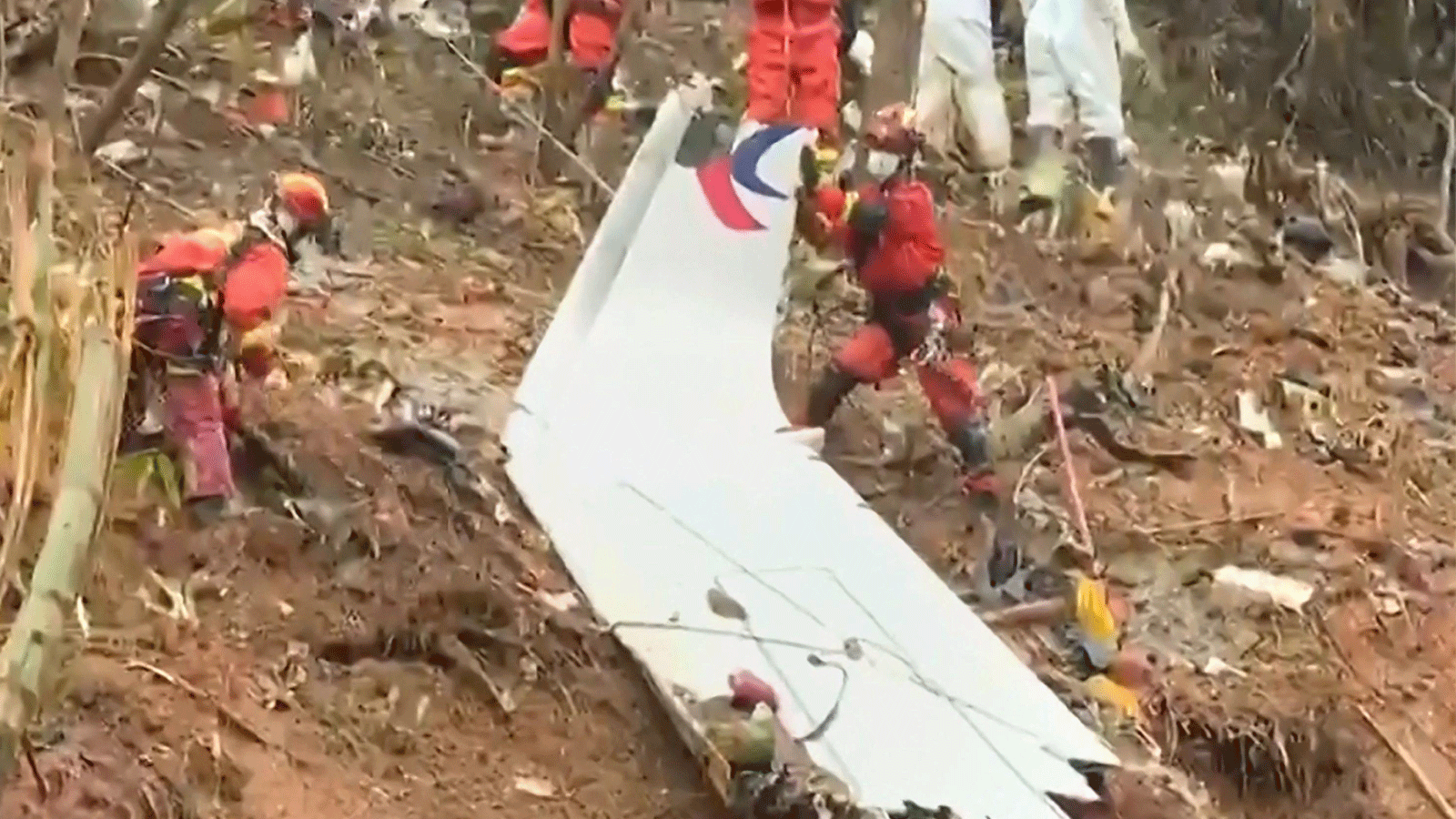  فرق الإنقاذ يسحبون قطعة من جسم الطائرة أثناء بحثهم في الموقع حيث تحطمت طائرة ركاب تابعة لشركة China Eastern على سفح جبل بالقرب من Wuzhou في منطقة Guangxi جنوب الصين.