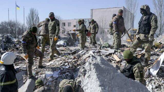 جنود أوكرانيون يبحثون عن جثث بين حطام المدرسة العسكرية التي أصيبت بصواريخ روسية في ميكولايف، جنوب أوكرانيا، في 19 مارس 2022