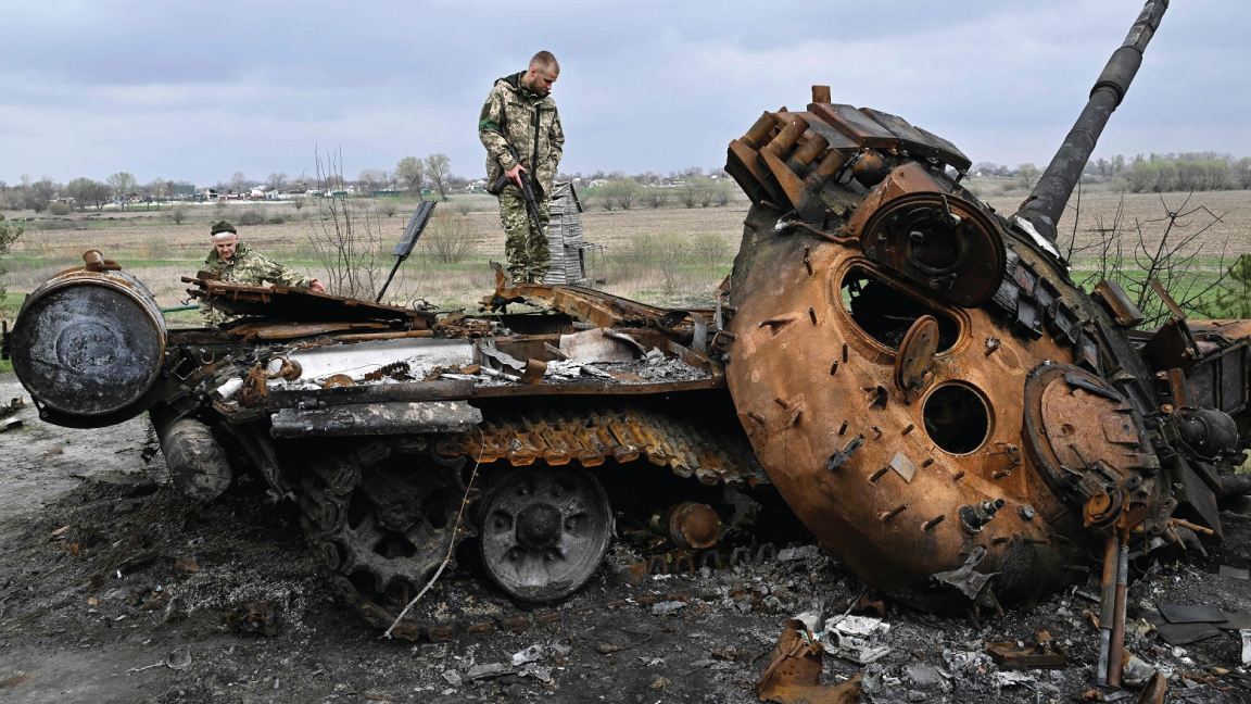 جنود أوكرانيون على دبابة روسية مدمرة في قرية روسانيف في ضواحي كييف، في 16 أبريل 2022