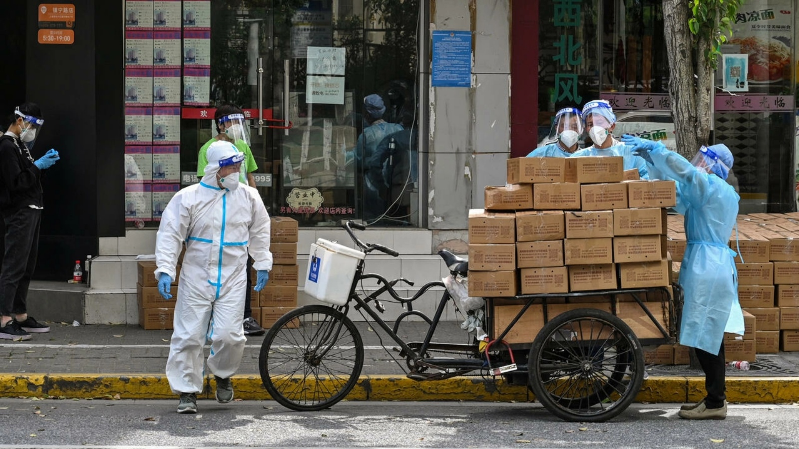 عمال ببزات واقية يحمّلون صناديق في عربة في حي في منطقة جينغآن في شنغهاي بتاريخ 18 مايو 2022