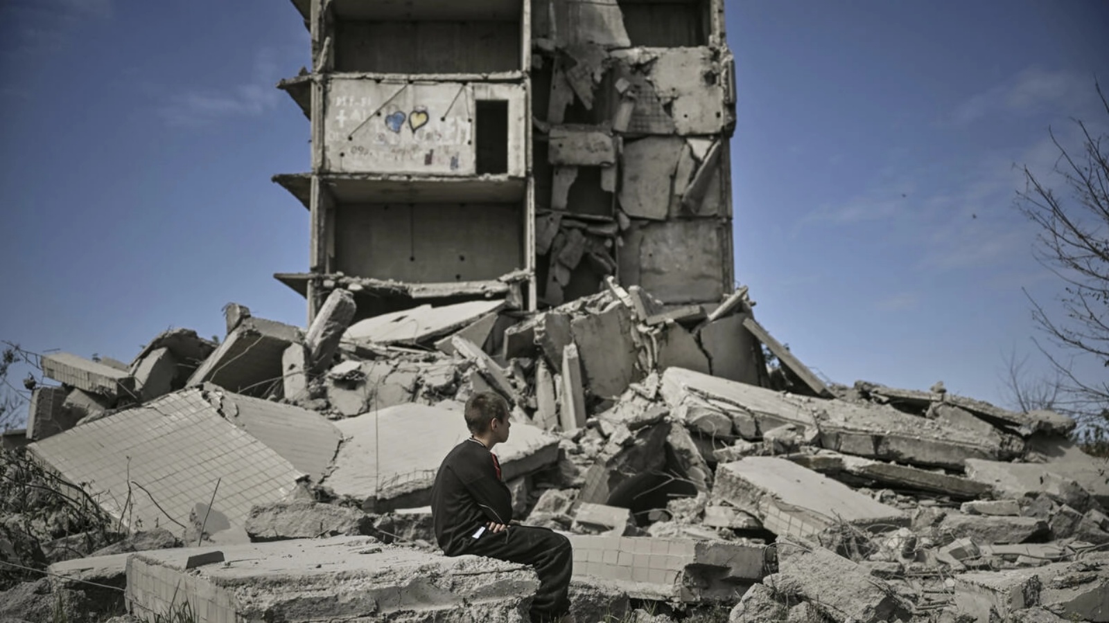 طفل يجلس على أنقاض منزله بعد قصف المباني السكنية في دونباس