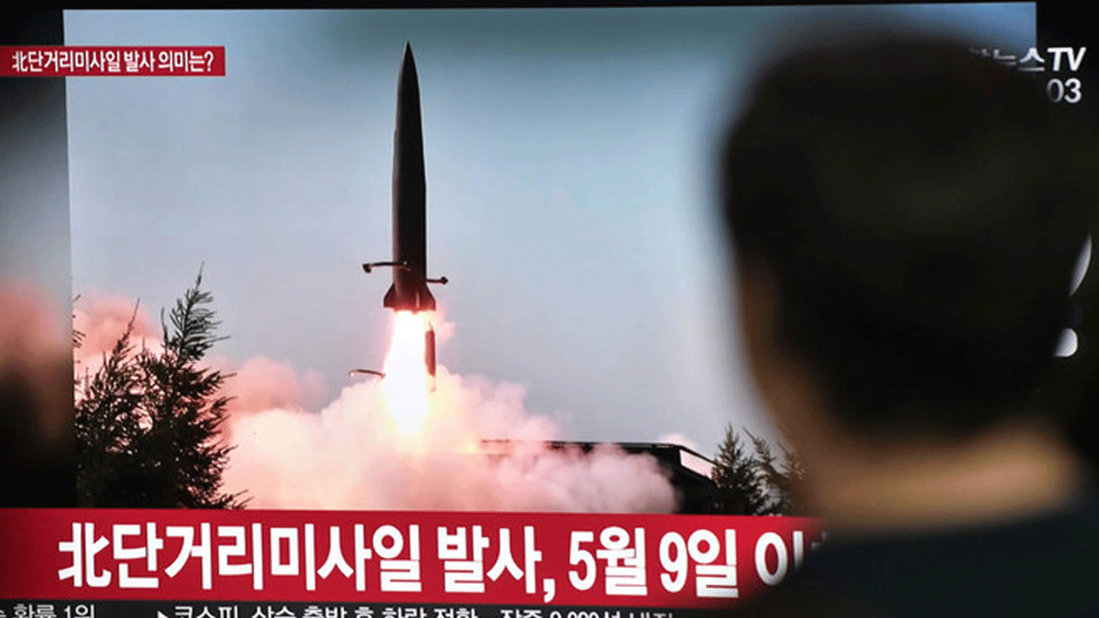 مواطن في كوريا الشمالية يراقب صاروخاً باليستياً أطلقته بلاده