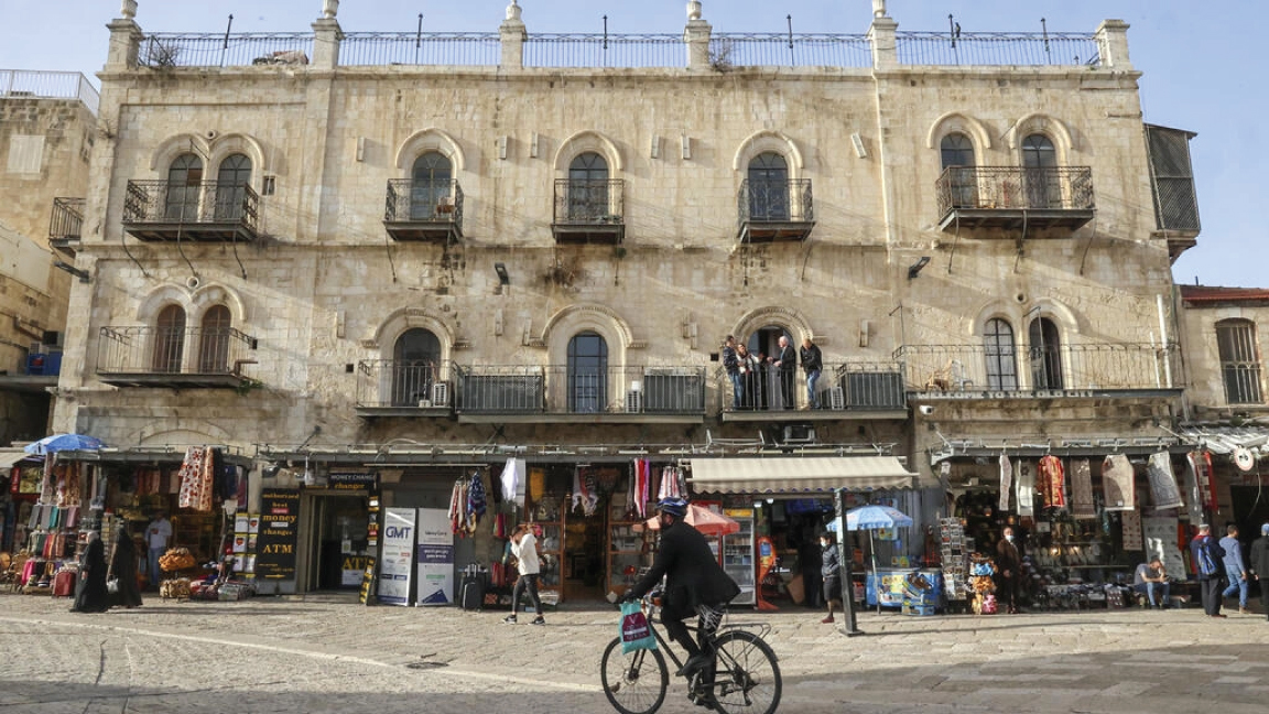 رجل يقود دراجة هوائية يمر من أمام فندق البترا في ميدان عمر بن الخطاب قرب باب يافا في البلدة القديمة من القدس الشرقية المحتلة والمهدد بالإخلاء لصالح الجمعيات الاستيطانية في 29 مارس 2022