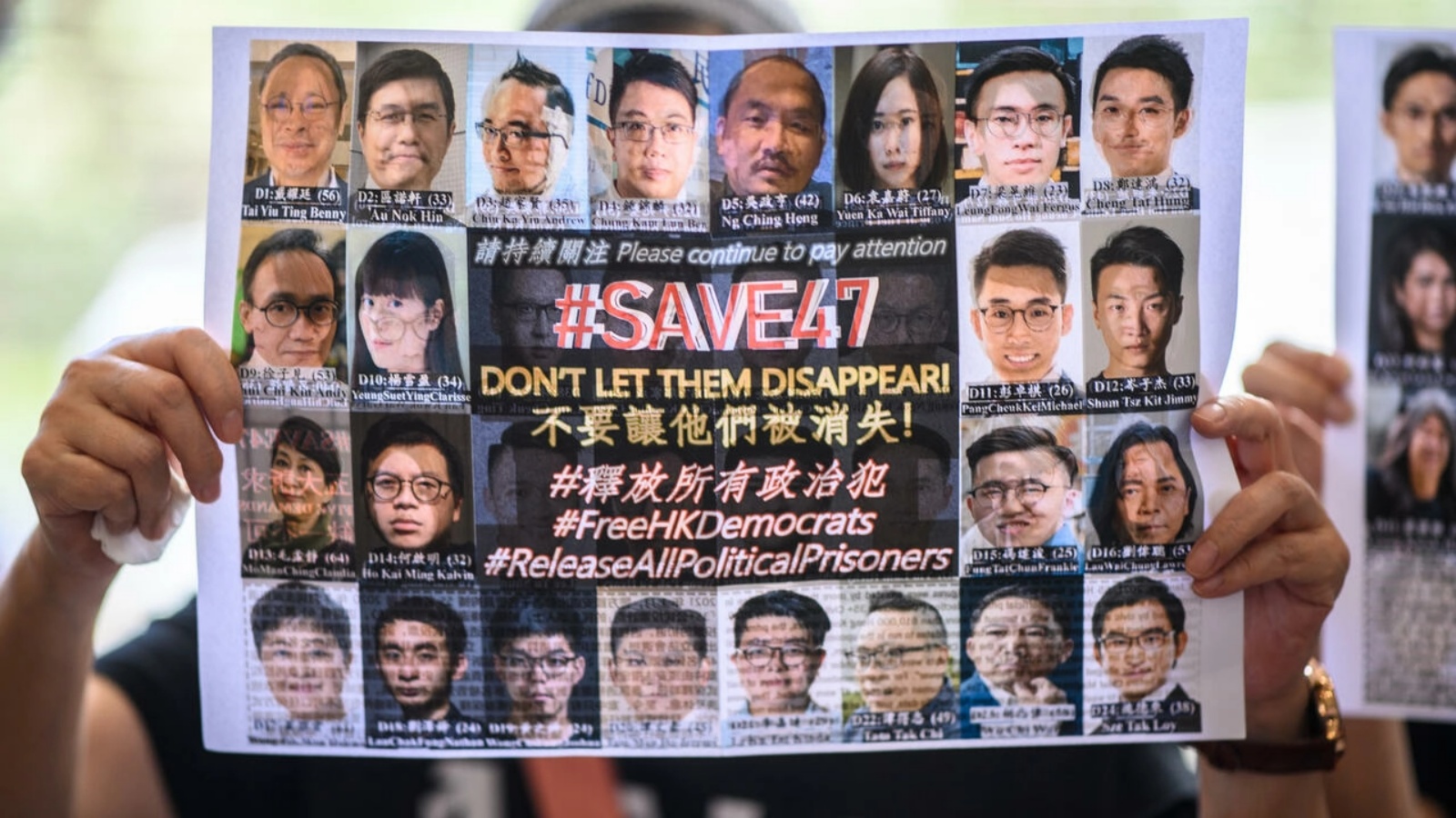 صورة يرفعها شخص للناشطين الـ47 المدافعين عن الديموقراطية الذين يحاكمون في هونغ كونغ بتاريخ 8 يوليو 2021