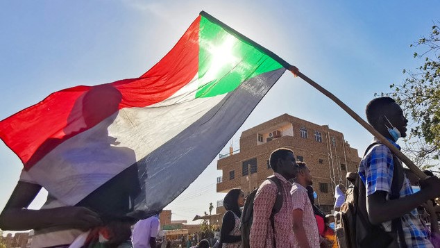 رجل سوداني يرفع العلم الوطني خلال احتجاج على الانقلاب العسكري في أكتوبر 2021