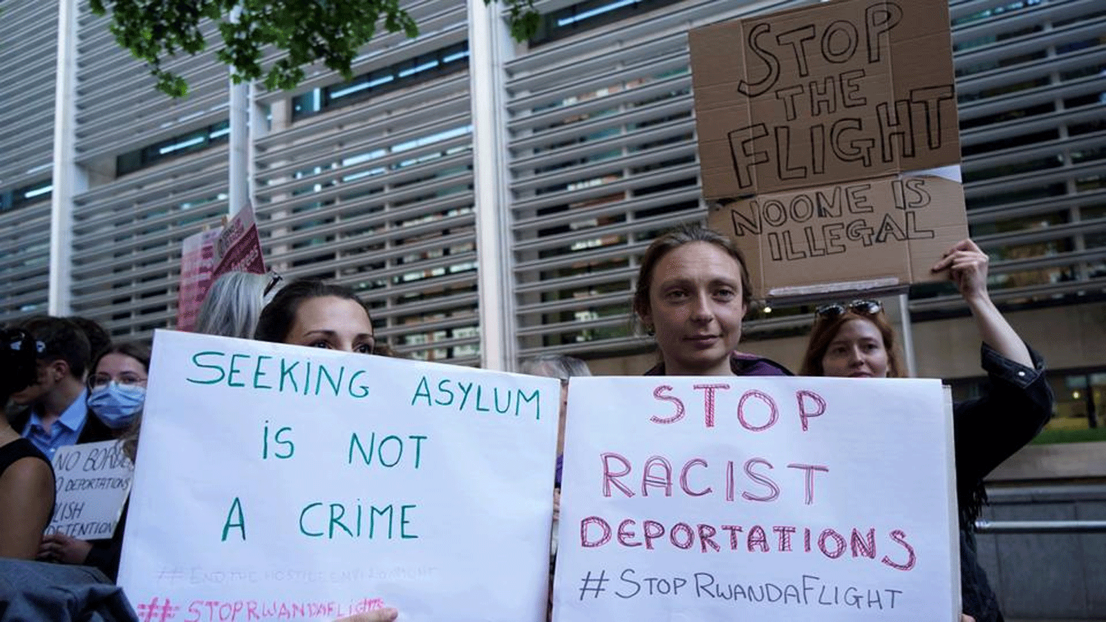 متظاهرون يحملون لافتات أثناء تجمعهم خارج وزارة الداخلية في وسط لندن للتظاهر ضد خطة حكومة المملكة المتحدة لترحيل طالبي اللجوء إلى رواندا