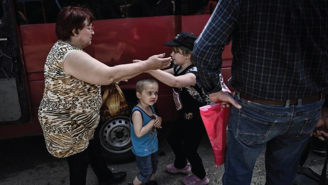 امرأة تعانق أطفالاً أثناء إجلاؤهم من مدينة سلوفيانسك شرقي أوكرانيا في 4 يونيو 2022