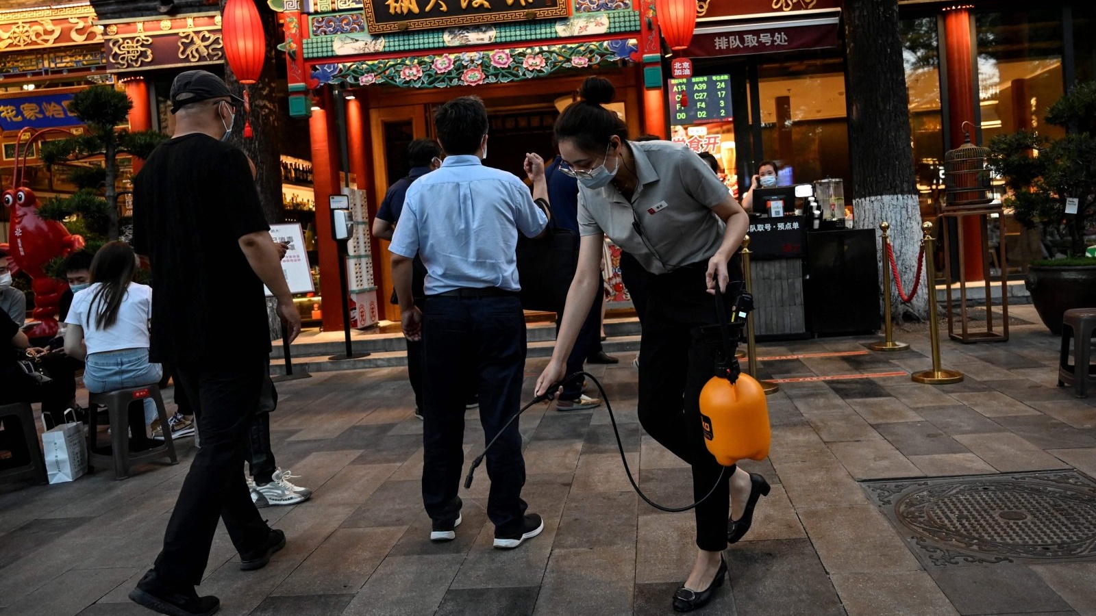 موظفة ترش معقماً خارج مطعم على طول شارع في بكين، الصين. 6 يونيو 2022
