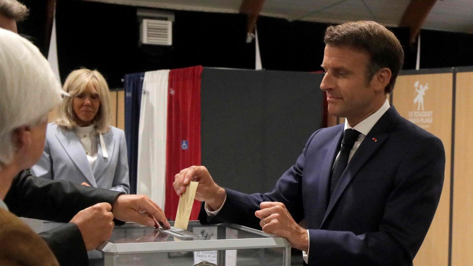 الرئيس الفرنسي إيمانويل ماكرون (يمين) يدلي بصوته إلى جانب زوجته بريجيت ماكرون خلال المرحلة الثانية من الانتخابات البرلمانية الفرنسية في مركز اقتراع في لوتوكيه شمال فرنسا ، 19 يونيو 2022