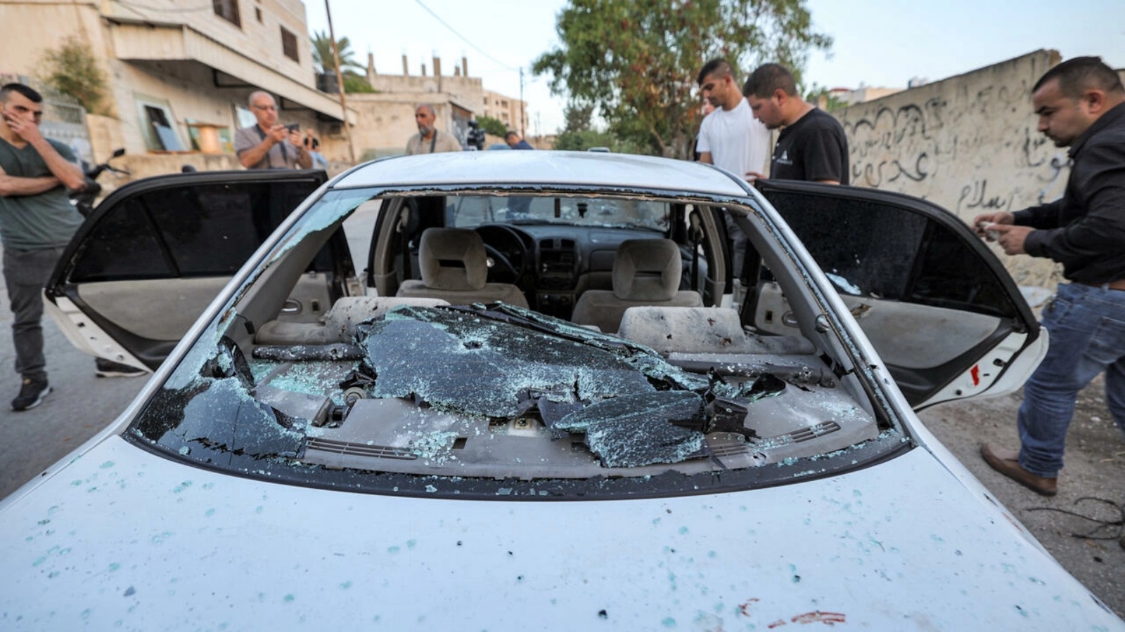 مواطنون يتفقدون سيارة مخترقة بالرصاص استشهد خلالها ثلاثة فلسطينيين في عملية نفذتها القوات الاسرائيلية في جنين بالضفة الغربية المحتلة
