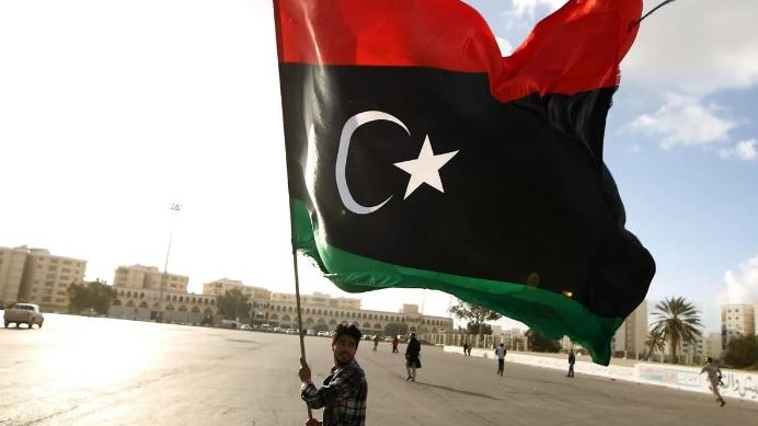 صورة من الأرشيف لمواطن ليبي يحمل علم بلاده بعد الثورة