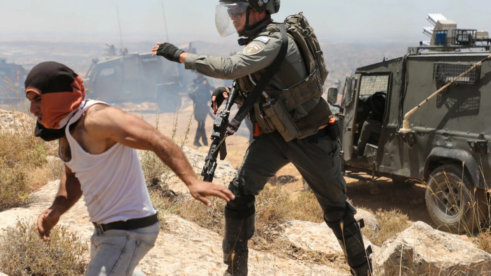 جندي إسرائيلي يلاحق متظاهراً فلسطينياً خلال تظاهرة ضد الاستيطان في قرية ترقوميا جنوب الضفة الغربية المحتلة في 11 يونيو 2022 