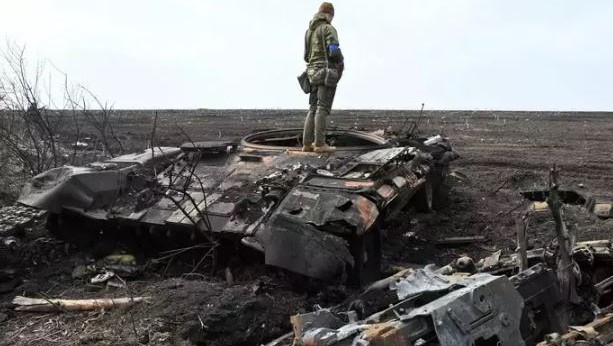 جندي أوكراني يقف على حطام دبابة روسية محترقة خارج قرية مالا روغان، شرق خاركيف، في 1 أبريل، وسط الغزو الروسي لأوكرانيا