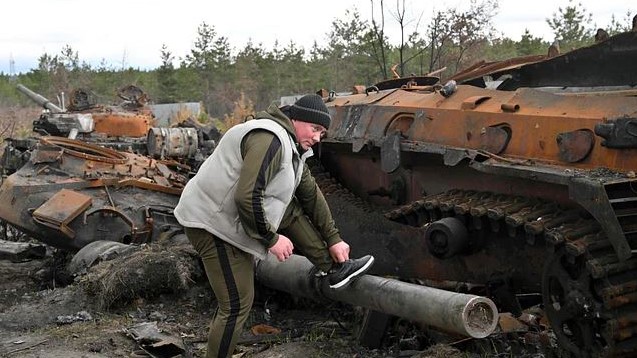 أوكراني يشد وثاق حذائه على فوهة دبابة روسية مدمرة في قرية أندرييفكا في منطقة كييف في 17 أبريل 2022