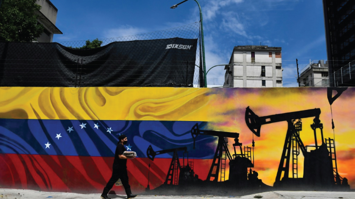 رجل يمر أمام جدارية تمثل مضخة نفط وعلم فنزويلا في احد شوارع كراكاس في 26 مايو 2022
