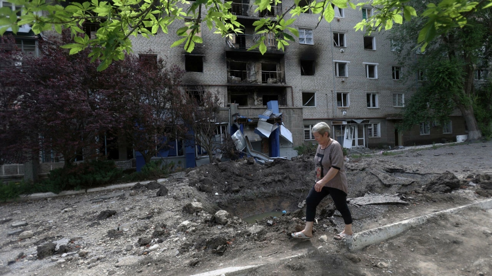 امرأة تمر أمام مبنى تعرض للقصف في سيفيرسك في منطقة دونيتسك في 23 يونيو 2022
