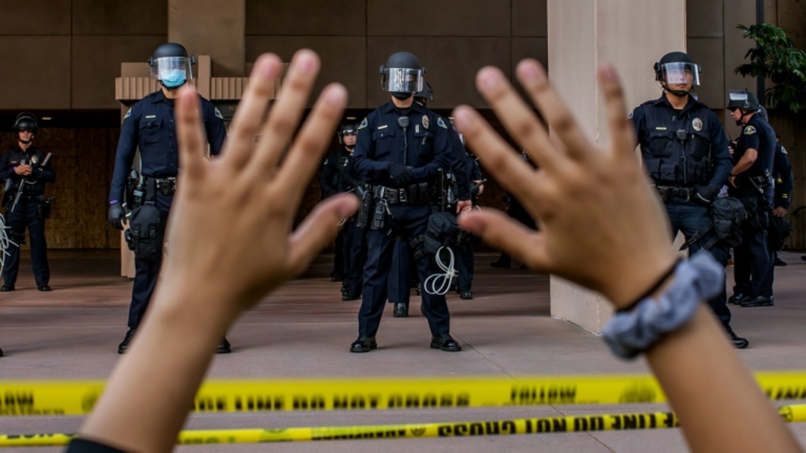 متظاهرة ترفع يديها وهي راكعة أمام الشرطة في سيتي هول في أنهايم، كاليفورنيا، 1 يونيو، 2020