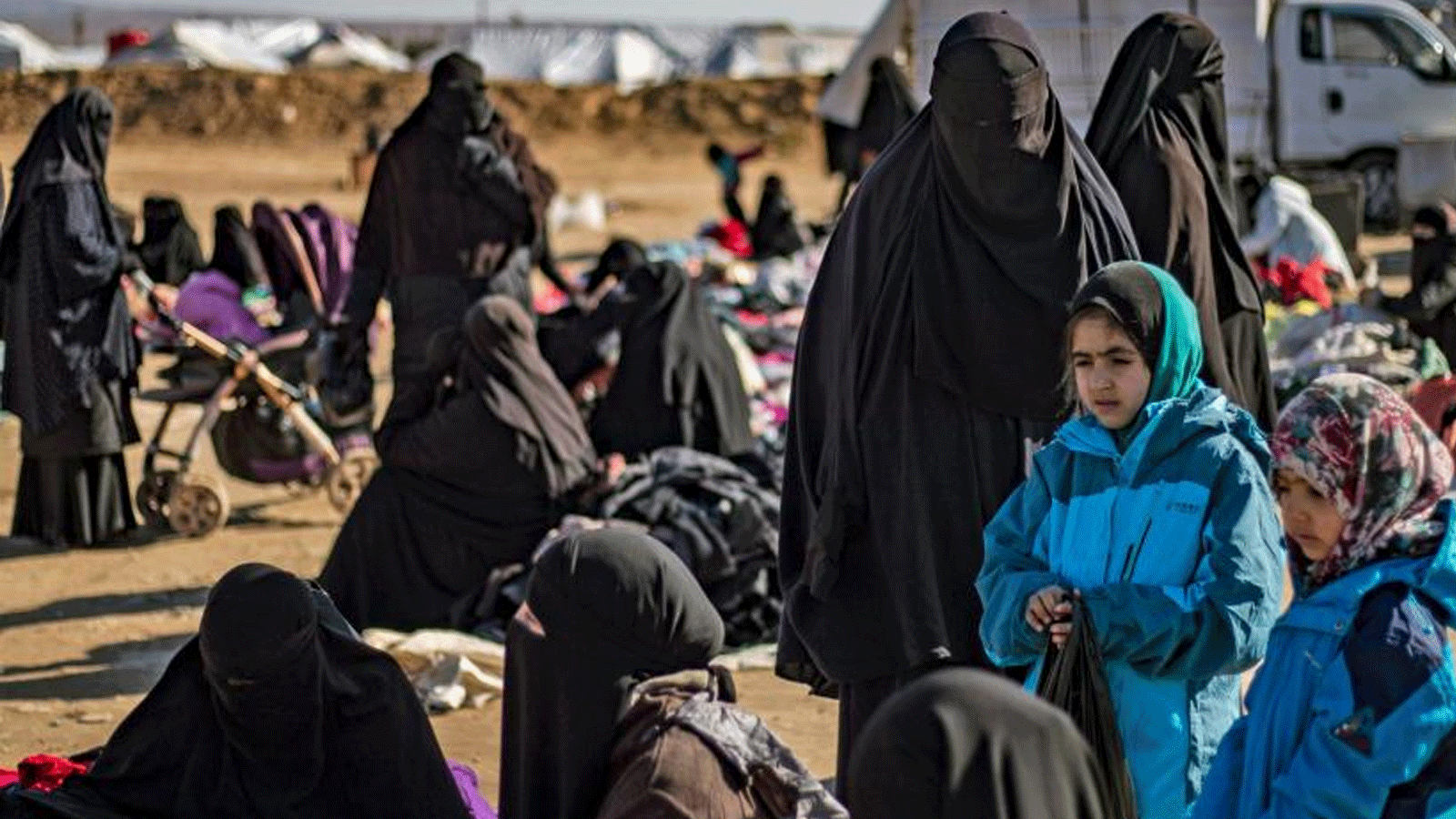 نساء وأطفال يجلسون في الهواء الطلق على الأرض في مخيم الهول الذي يديره الأكراد للنازحين في محافظة الحسكة في شمال شرق سوريا في 14 كانون الثاني / يناير 2020، حيث تُحتجز عائلات مقاتلي تنظيم الدولة الإسلامية.