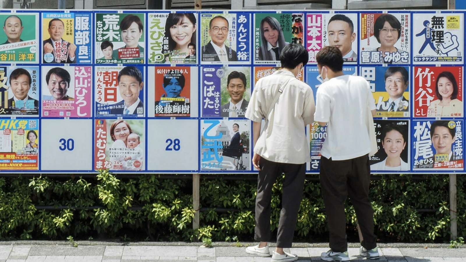أشخاص ينظرون إلى ملصقات الحملة الانتخابية لانتخابات مجلس الشيوخ في اليابان في 10 يوليو 2022