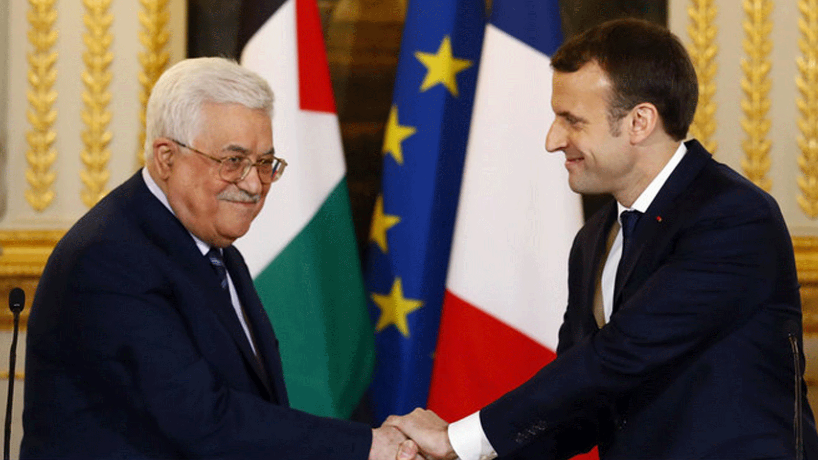 صورة أرشيفية للرئيس الفرنسي إيمانويل ماكرون مصافحاً الرئيس الفلسطيني محمود عباس