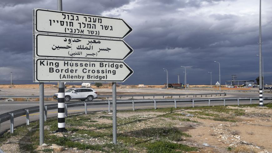 سيارة تمر عبر لافتة طريق تشير إلى نقطة عبور جسر اللنبي إلى الأردن (في الخلفية)، في مدينة أريحا، الضفة الغربية، 28 يناير 2021