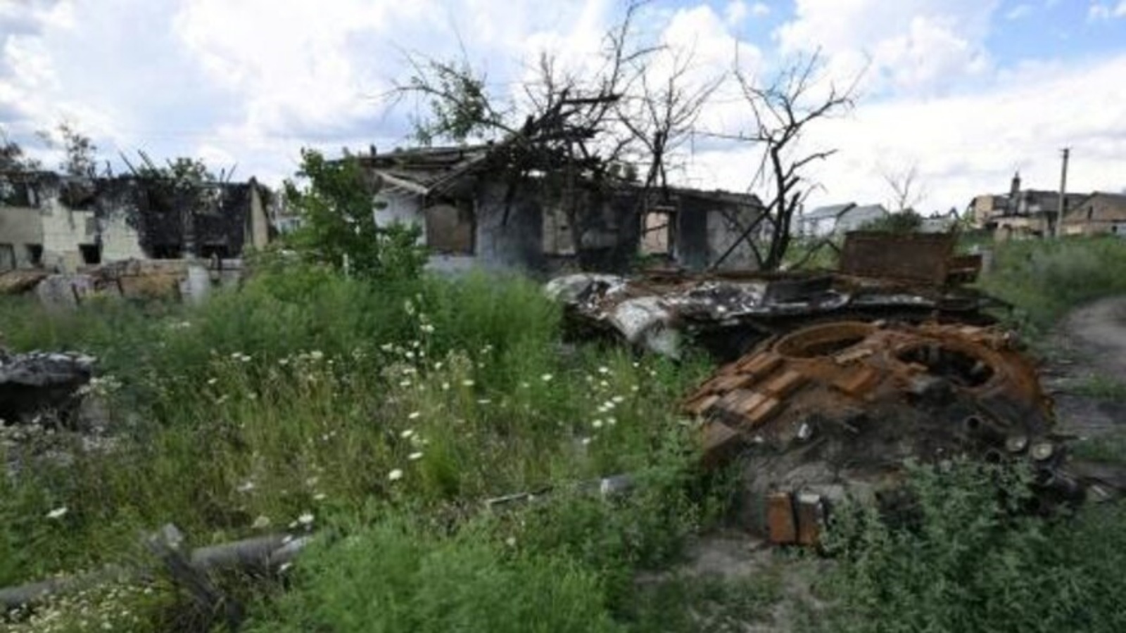  هيكل دبابة روسية مدمرة قرب منزل مهدوم في قرية مالا روغان بمنطقة خاركيف بشمال شرق أوكرانيا في 28 يوليو 2022