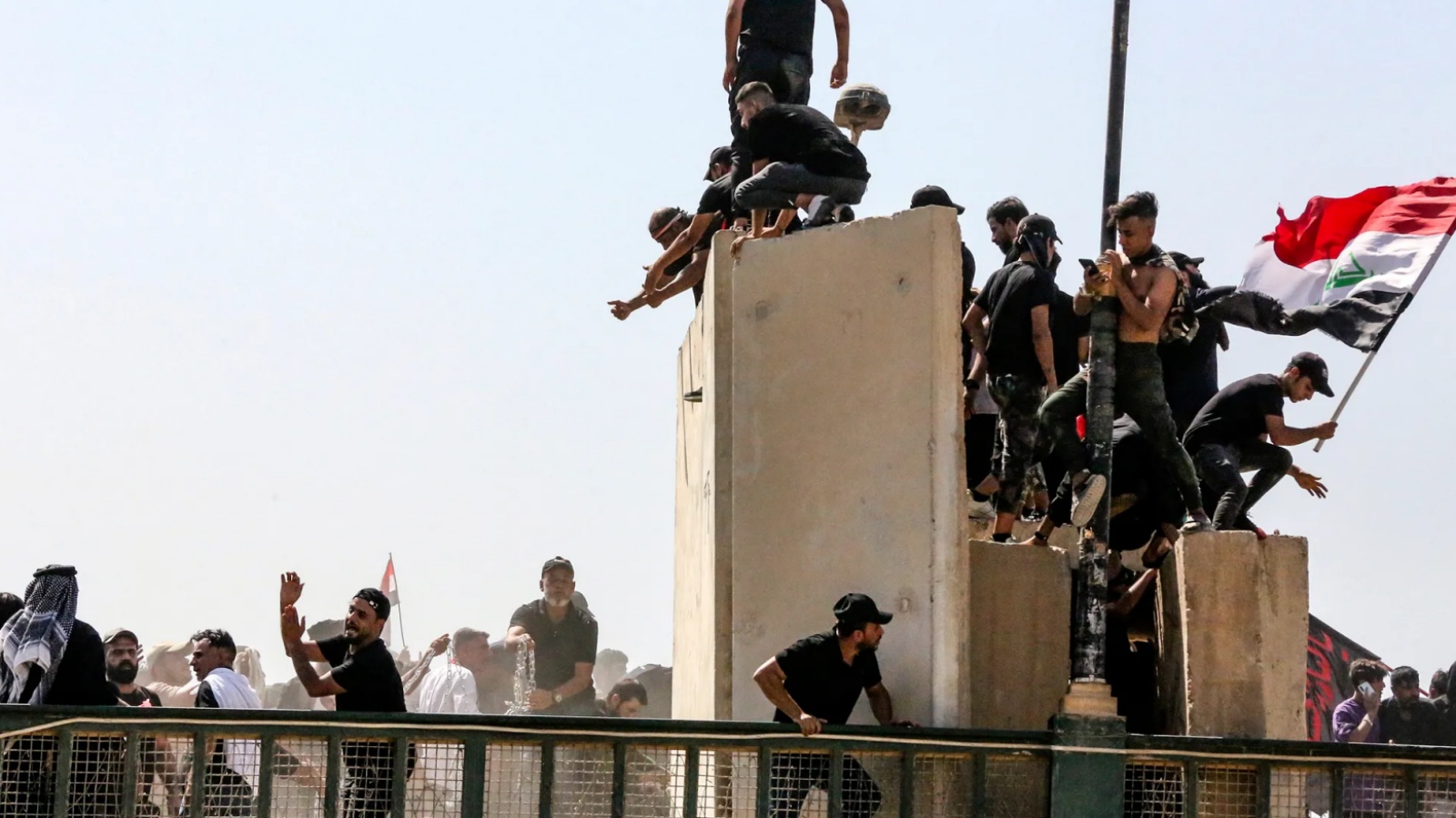 متظاهرون عراقيون يتسلّقون الحواجز الاسمنتية التي تمنع عبور جسر الجمهورية ويسقطون بعضها في 30 يوليو 2022