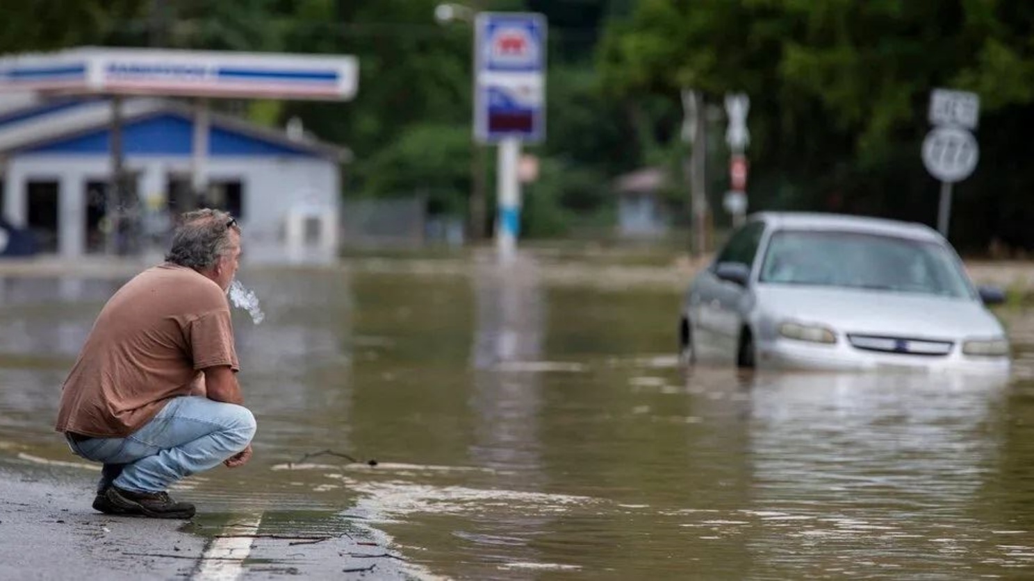رجل على رصيف طريق غمرته مياه الفيضانات في كنتاكي