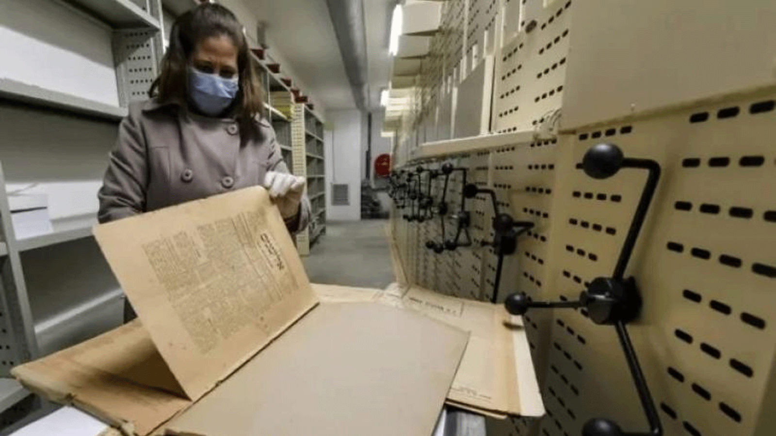 عاملة ترميم بالمكتبة الوطنية التونسية، تحفظ الصحف القديمة، في أرشيف المؤسسة بالعاصمة تونس. 26 مانون الثاني\يناير 2022.