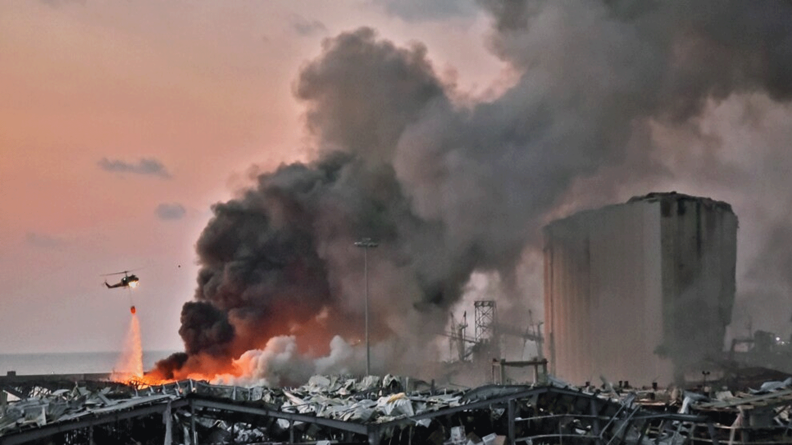 طائرة مروحية تخمد حريقًا في موقع انفجار بميناء العاصمة اللبنانية بيروت في 4 آب / أغسطس 2020.