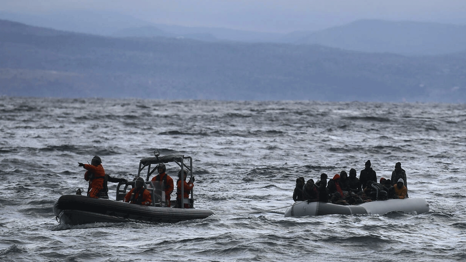 صورة أرشيفية لزورق ينقل عشرات اللاجئين والمهاجرين، يتم سحبه باتجاه جزيرة ليسبوس اليونانية، بعدما أنقذته سفينة حربية أثناء عبورهم البحر بين تركيا واليونان في 29 شباط\ فبراير 2020