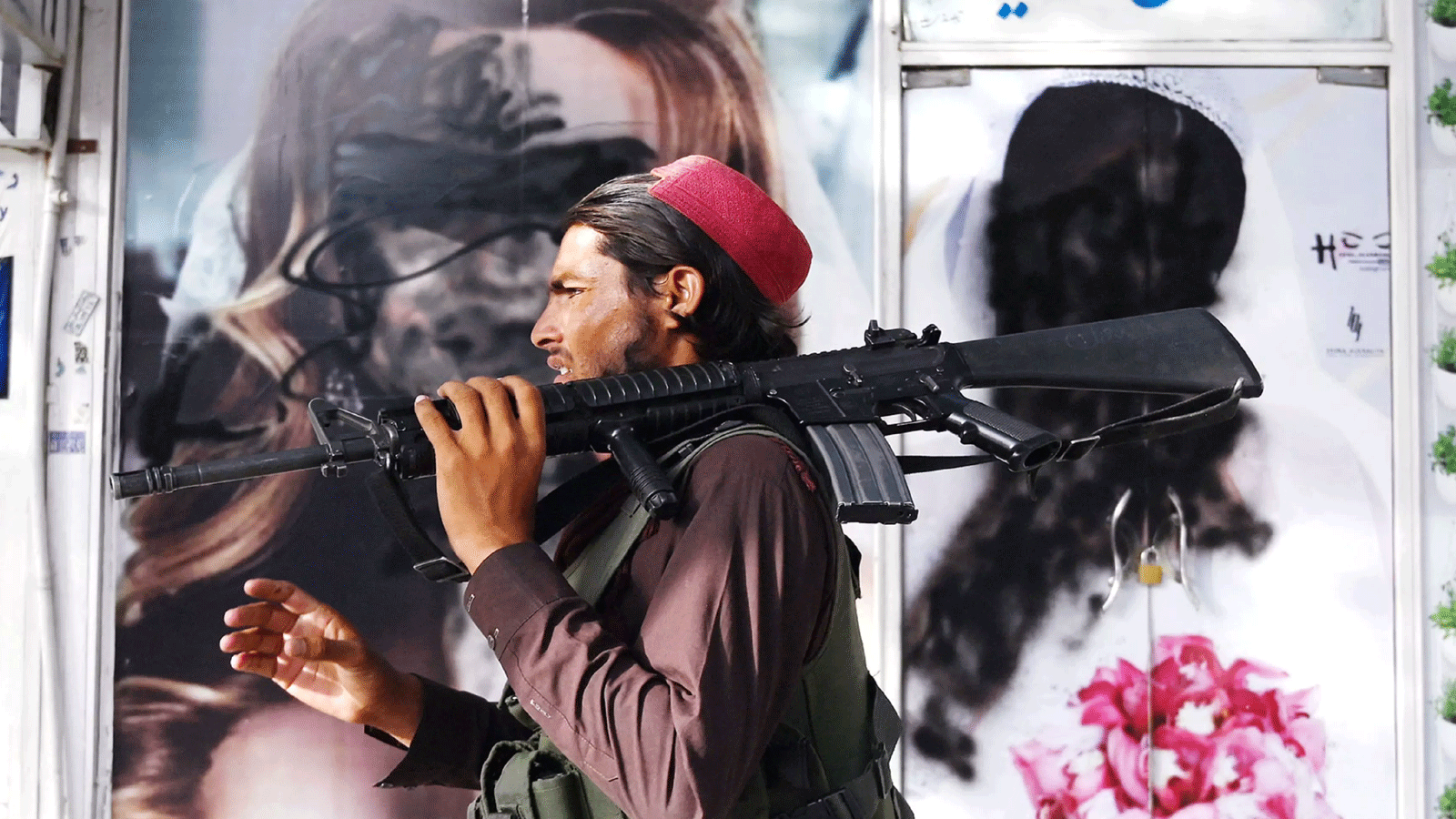 مقاتل من طالبان يمر أمام صالون تجميل تلطخت صور النساء على واجهاته بالشخابيط بعد أن استولت طالبان على كابول في آب\ أغسطس 2021