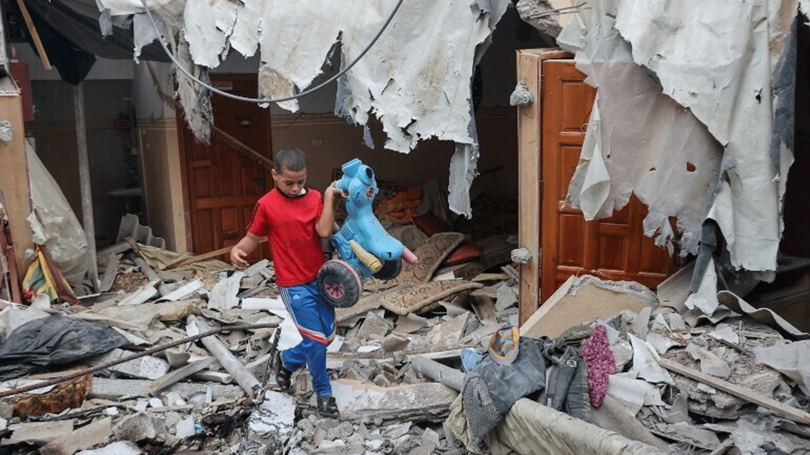 فتى فلسطيني ينقذ لعبة من بين أنقاض منزله الذي دُمِّر خلال الأيام الثلاثة الأخيرة من الهجمات الإسرائيلية قبل الهدنة، في مدينة رفح جنوب قطاع غزة، في 8 آب\ أغسطس.