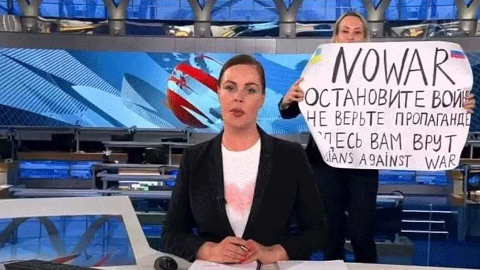 مارينا أوفسيانيكوفا محررة القناة الأولى الروسية تحمل ملصقًا كُتِب عليه 