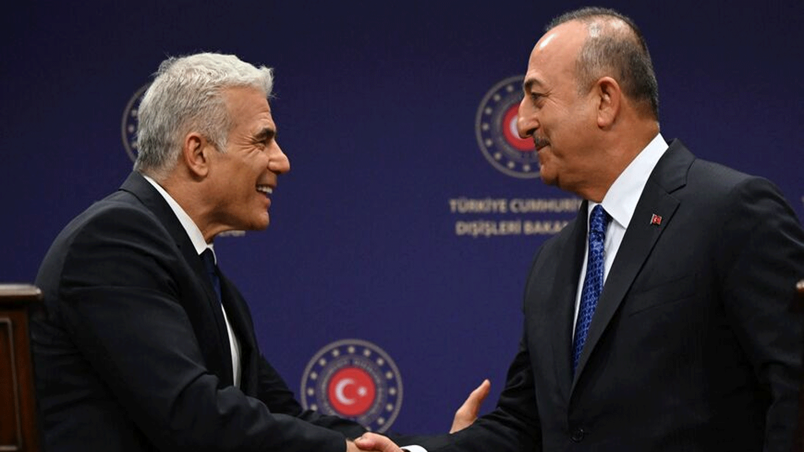 وزير الخارجية التركي مولود جاويش أوغلو (إلى اليمين) ووزير الخارجية الإسرائيلي يائير لابيد (إلى اليسار) يتصافحان خلال مؤتمر صحفي في 23 حزيران\يونيو 2022 في أنقرة.
