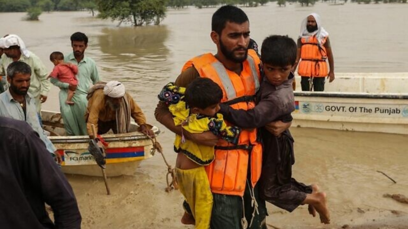 عمال الإنقاذ يساعدون في إجلاء الباكستانيين المتضررين من الفيضانات من منازلهم التي ضربتها الفيضانات بعد هطول أمطار موسمية غزيرة في منطقة راجانبور بمقاطعة البنجاب في 27 أغسطس 2022