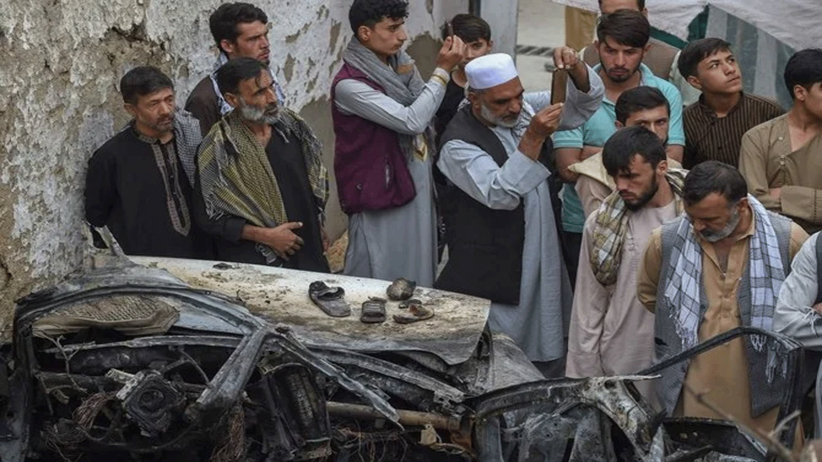 سكان أفغان وأفراد عائلات الضحايا يتجمعون بجوار سيارة مدمرة داخل منزل، بعد يومٍ من غارة جوية أميركية بطائرة بدون طيار في كابول.
