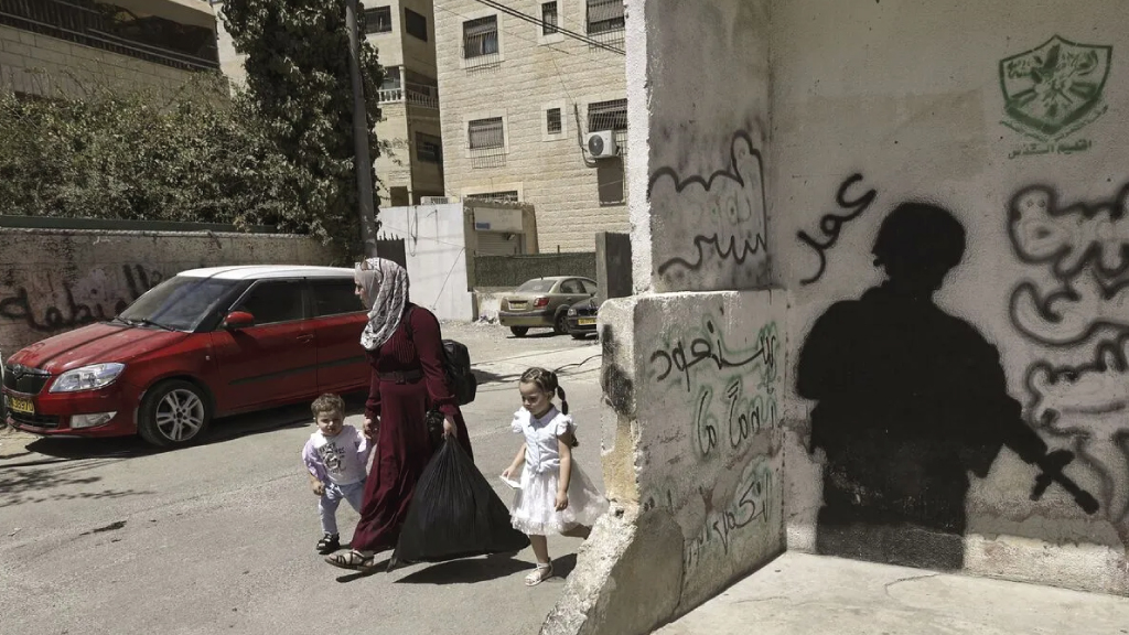 فلسطينية مع طفليها في شارع بضاحية كفر عقاب الفلسطينية في القدس الشرقية قرب مدينة رام الله بالضفة الغربية، 25 أغسطس 2022