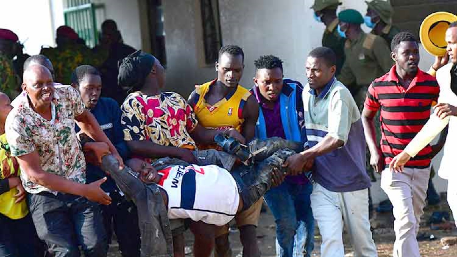 أشخاص يحملون رجلاً مصاباً بينما تتدخل قوات الأمن الكينية بعد تدافع عند مدخل مركز موي الرياضي الدولي في كاساراني في نيروبي، كينيا. الثلاثاء 13 سبتمبر 2022