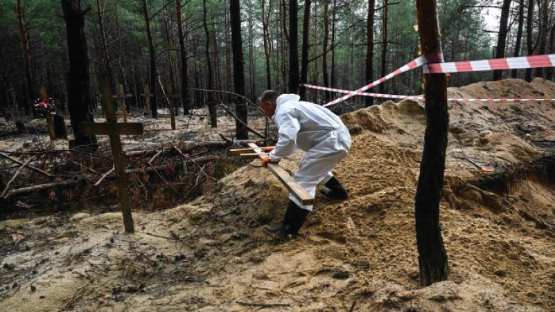 فني الطب الشرعي يحرك صليبا في غابة على مشارف إيزيوم ، شرق أوكرانيا في 16 سبتمبر 2022