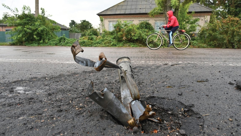 بقايا قذيفة انفجرت في فيربيفكا، أوكرانيا، بينما يمر دراج في المكان
